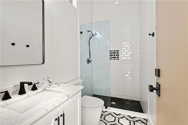 bathroom with toilet, tiled shower, and vanity