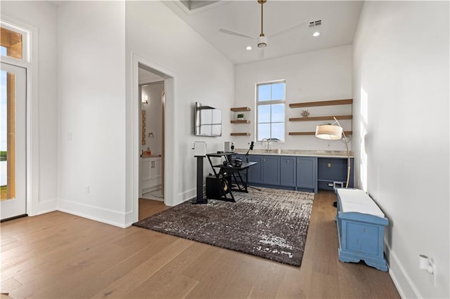 kitchen featuring open shelves, wood finished floors, baseboards, and a sink