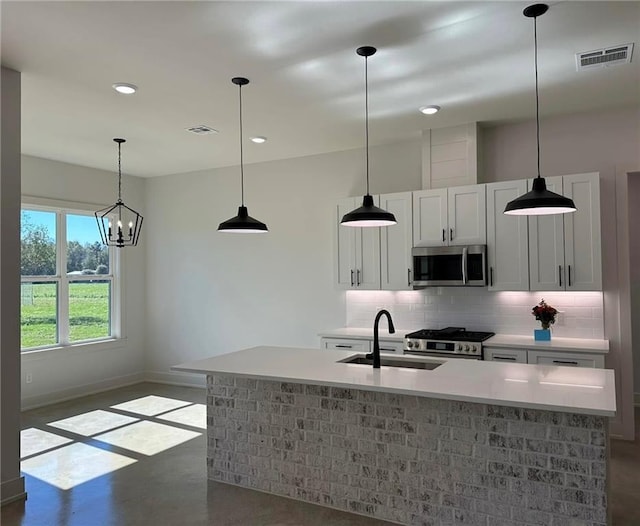 kitchen featuring a sink, concrete flooring, stainless steel microwave, range, and backsplash