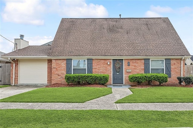 view of front facade featuring a shingled roof, concrete driveway, an attached garage, a front yard, and a chimney