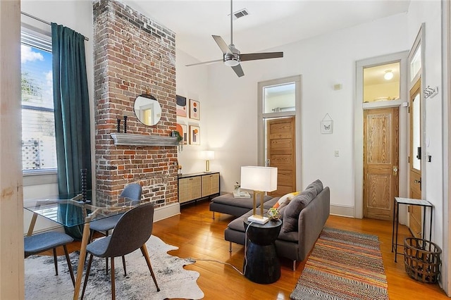 living area with baseboards, a ceiling fan, wood finished floors, and visible vents
