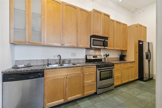 kitchen with a sink, glass insert cabinets, stainless steel appliances, and dark stone countertops