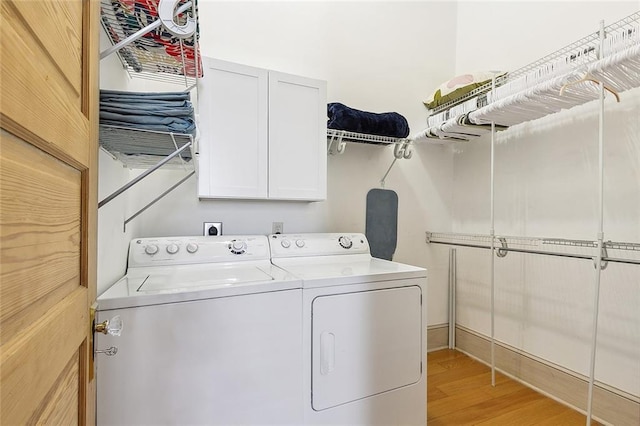 washroom with light wood-style flooring, cabinet space, and washer and dryer
