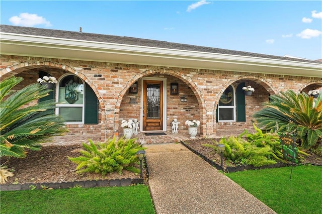 view of exterior entry featuring brick siding and a porch