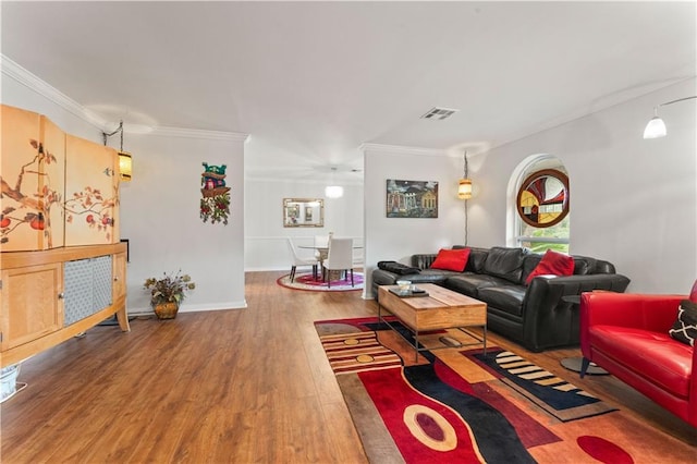 living area with crown molding, wood finished floors, visible vents, and baseboards