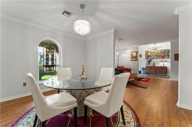 dining space featuring visible vents, a notable chandelier, hardwood / wood-style floors, and crown molding