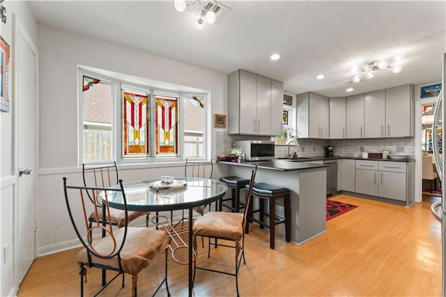 kitchen featuring dark countertops, appliances with stainless steel finishes, a peninsula, and gray cabinets