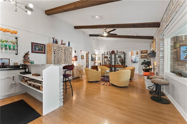 living room featuring baseboards, visible vents, light wood finished floors, vaulted ceiling with beams, and ceiling fan