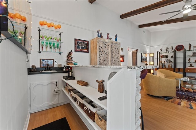 interior space with beamed ceiling, ceiling fan, and wood finished floors