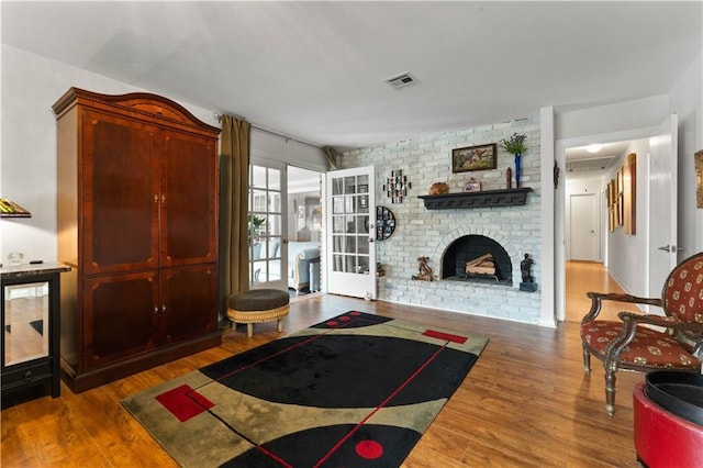 living room featuring visible vents, a fireplace, and wood finished floors