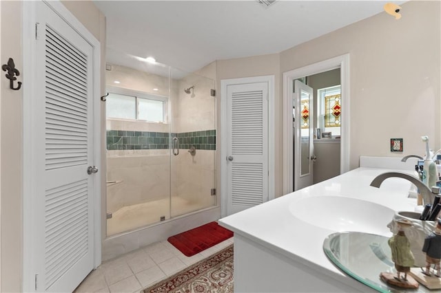 bathroom featuring a stall shower, a sink, a closet, tile patterned flooring, and double vanity