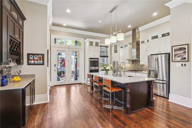 kitchen featuring light countertops, wall chimney range hood, dark wood-style floors, and appliances with stainless steel finishes