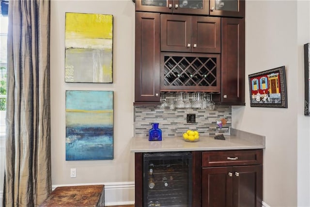 bar with baseboards, tasteful backsplash, beverage cooler, and a dry bar