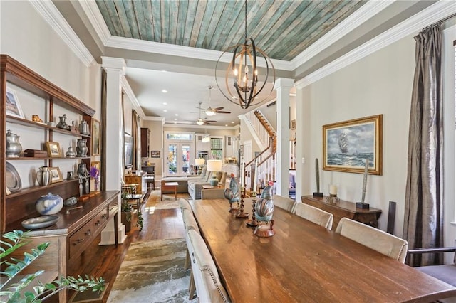 dining area with dark wood finished floors, stairway, ceiling fan with notable chandelier, and ornate columns