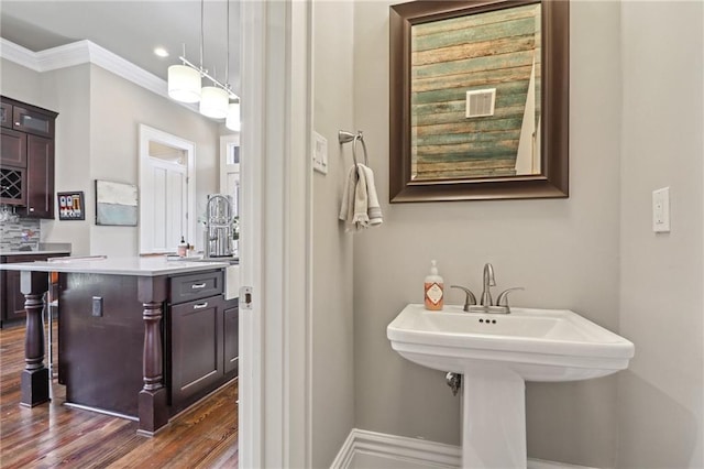 bathroom featuring ornamental molding, wood finished floors, tasteful backsplash, and a sink