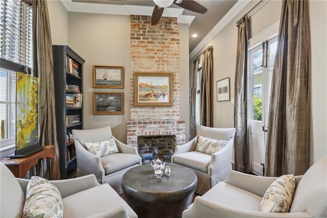 sitting room with a brick fireplace, a ceiling fan, and ornamental molding