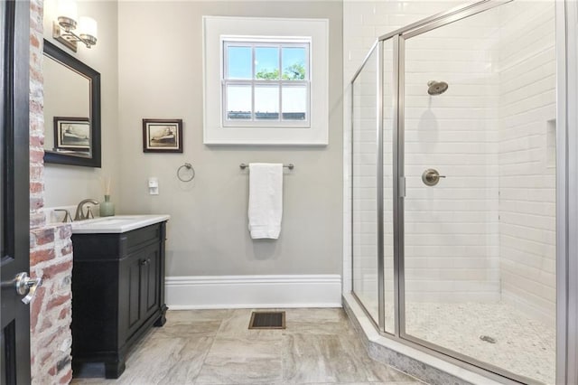 full bath with vanity, baseboards, visible vents, and a stall shower