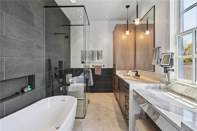 full bathroom featuring vanity, tile walls, a stall shower, and a freestanding bath