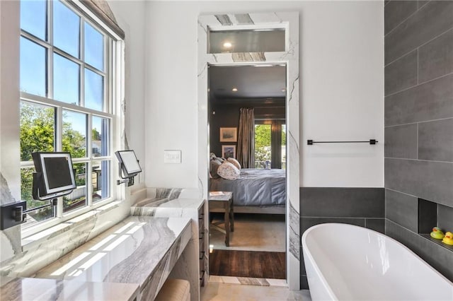 ensuite bathroom with a soaking tub, wood finished floors, and ensuite bathroom