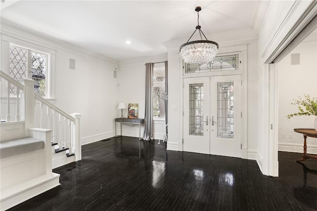 foyer with stairway, wood finished floors, an inviting chandelier, ornamental molding, and french doors