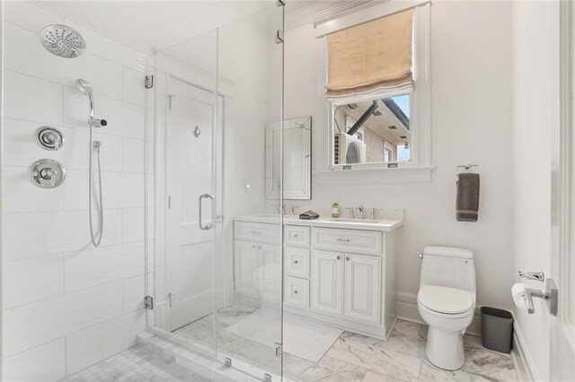 bathroom featuring toilet, double vanity, a stall shower, marble finish floor, and a sink