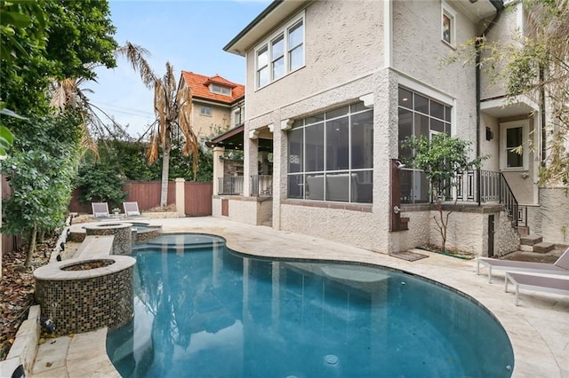 view of swimming pool featuring a patio area, fence, and a pool with connected hot tub