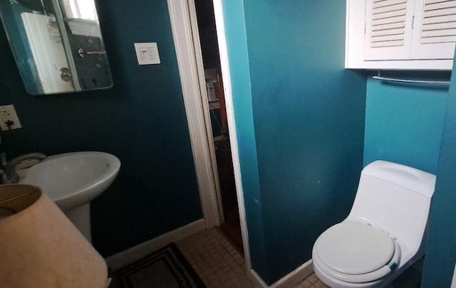 half bath featuring baseboards and toilet