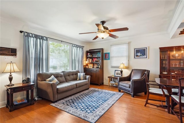 living room featuring crown molding, a ceiling fan, light wood-type flooring, and baseboards