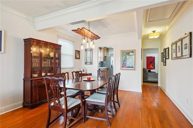 dining area with wood finished floors, baseboards, and ornamental molding