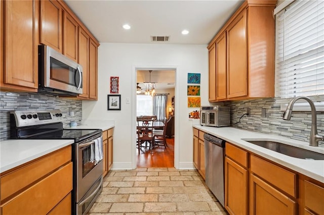 kitchen featuring visible vents, stainless steel appliances, light countertops, and a sink