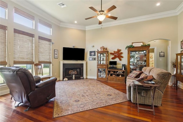 living area with a ceiling fan, crown molding, wood finished floors, and visible vents