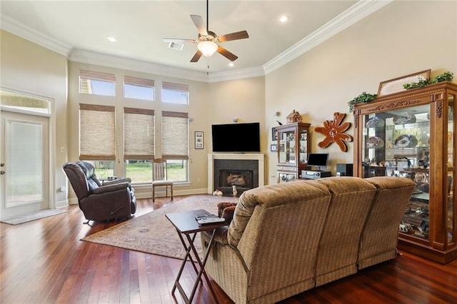 living room featuring dark wood-type flooring, a fireplace, visible vents, and ornamental molding