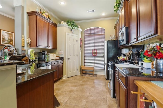 kitchen featuring visible vents, dark stone counters, stainless steel appliances, decorative backsplash, and crown molding