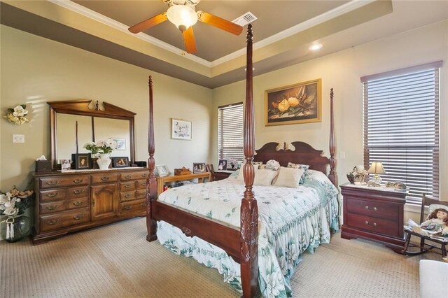 bedroom with a raised ceiling, ornamental molding, visible vents, and light carpet