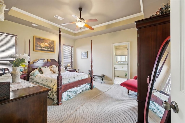 bedroom featuring visible vents, ornamental molding, ensuite bath, a raised ceiling, and a ceiling fan