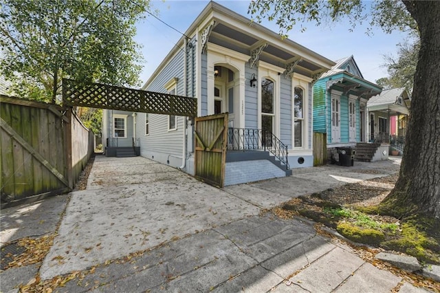 view of front facade featuring a detached carport, concrete driveway, and fence