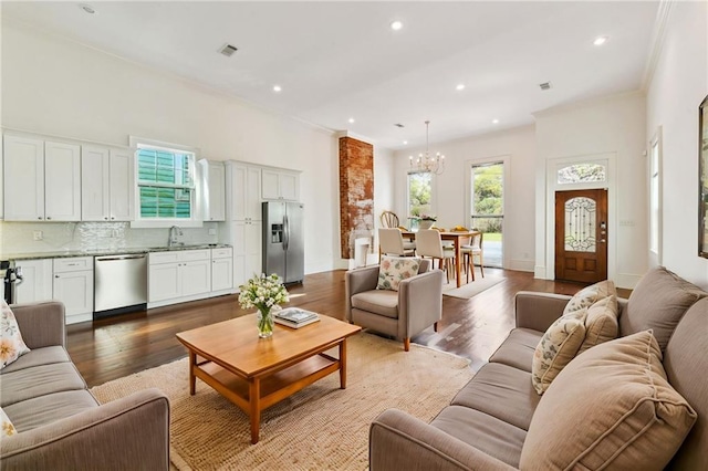 living room with recessed lighting, crown molding, an inviting chandelier, and wood finished floors