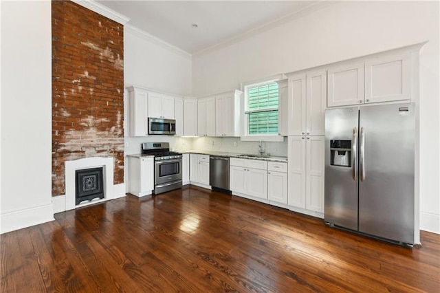 kitchen with dark wood-style floors, a sink, ornamental molding, stainless steel appliances, and a towering ceiling