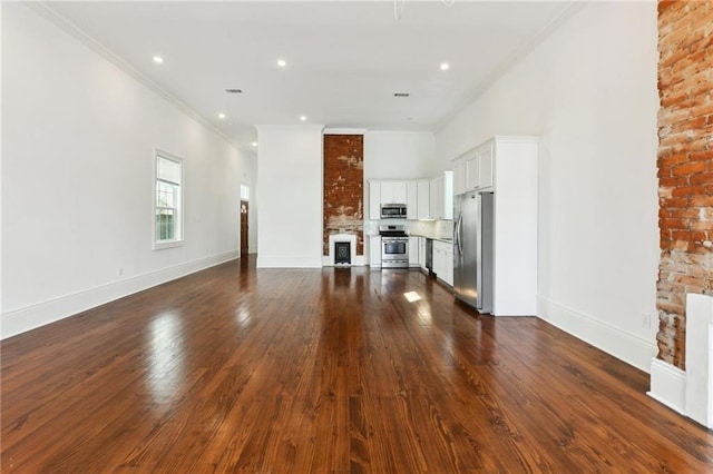 unfurnished living room with a towering ceiling, baseboards, ornamental molding, and dark wood-style flooring