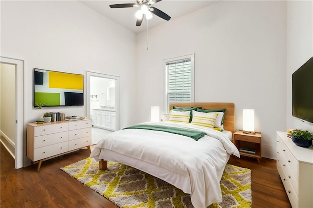 bedroom featuring dark wood-style floors, connected bathroom, a towering ceiling, and ceiling fan