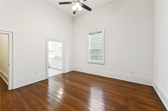 unfurnished bedroom with a ceiling fan, wood finished floors, baseboards, a high ceiling, and ensuite bathroom