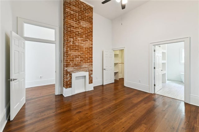 interior space featuring baseboards, ensuite bath, a towering ceiling, and hardwood / wood-style flooring