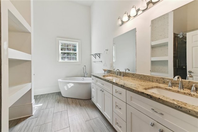 full bath featuring a sink, a freestanding tub, a stall shower, and double vanity