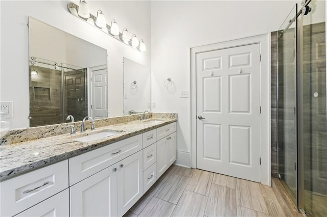 full bath featuring double vanity, a shower stall, and a sink