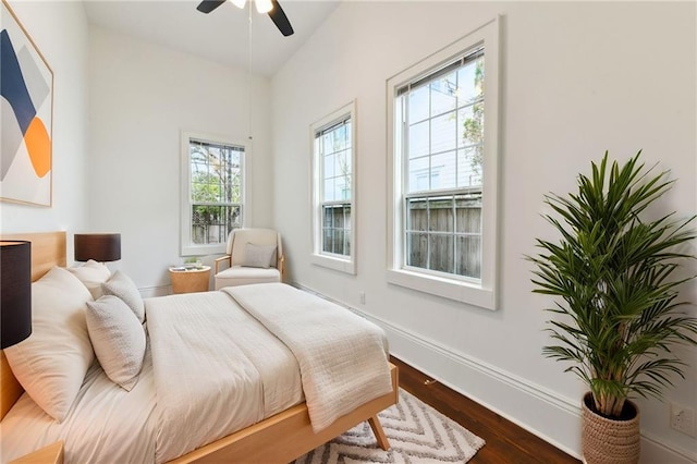 bedroom with ceiling fan, baseboards, lofted ceiling, and dark wood-style floors