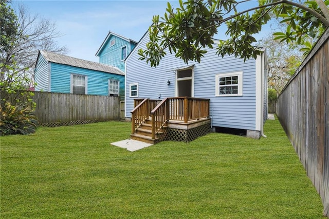 rear view of house with a deck, a lawn, and a fenced backyard