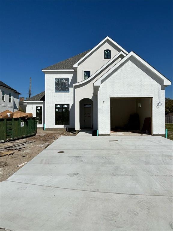 view of front facade featuring a shingled roof, stucco siding, and driveway