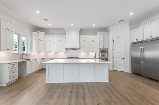 11 Khan Ct, Metairie, LA 70003 - kitchen featuring built in appliances, crown molding, a sink, tasteful backsplash, and custom exhaust hood
