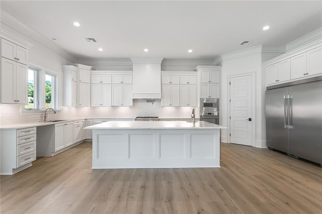11 Khan Ct, Metairie, LA 70003 - kitchen with built in appliances, crown molding, premium range hood, light countertops, and backsplash