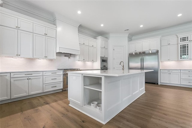 11 Khan Ct, Metairie, LA 70003 - kitchen featuring built in appliances, ornamental molding, tasteful backsplash, white cabinetry, and dark wood finished floors